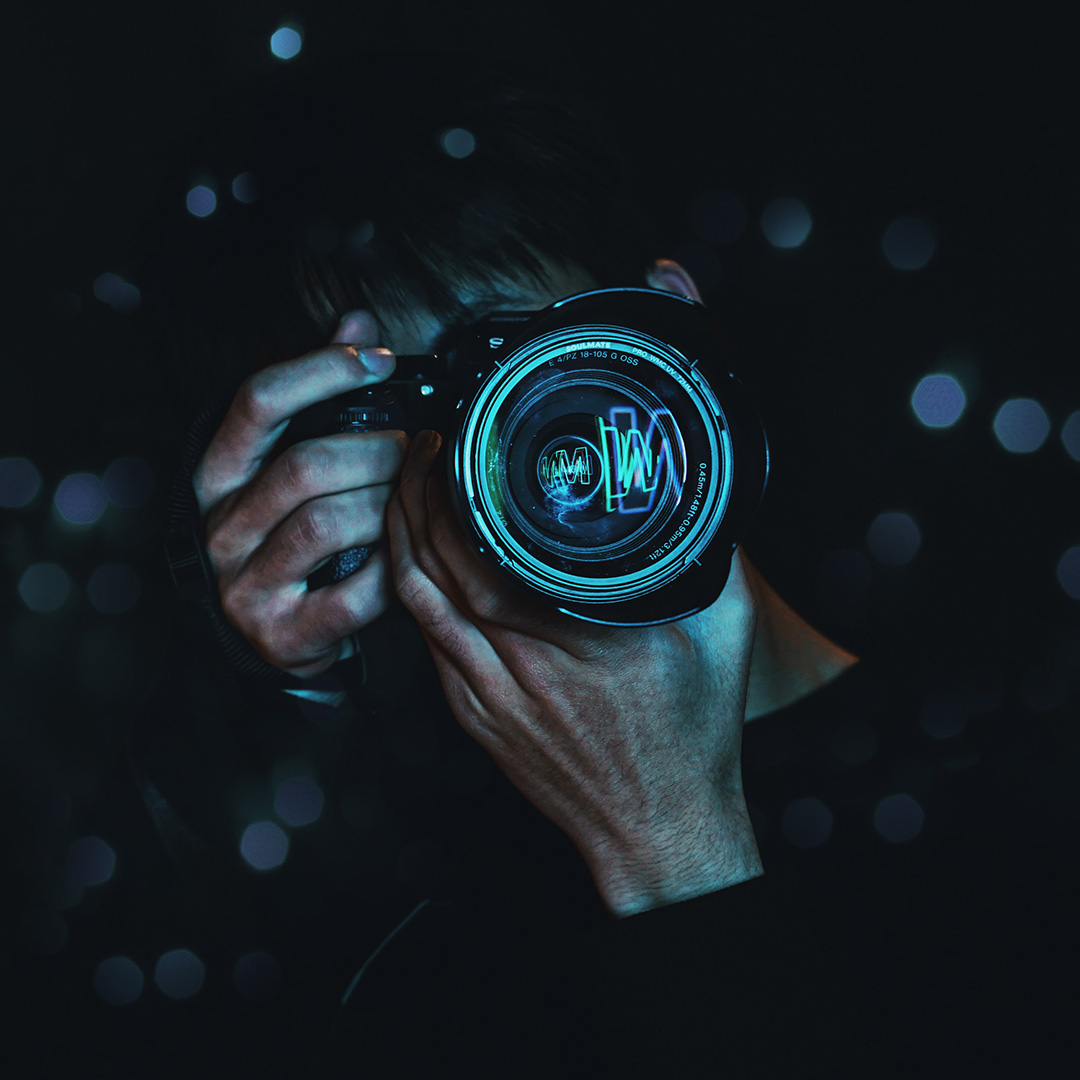 A photographer holding up a camera that is reflecting blue light from its lense